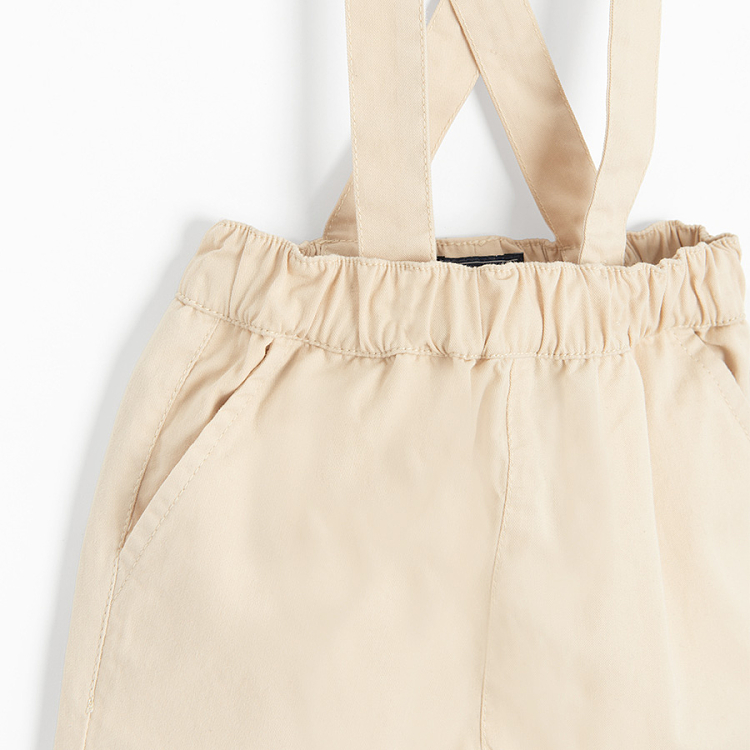 Brown bodysuit with bow tie and ecru pants with suspenders