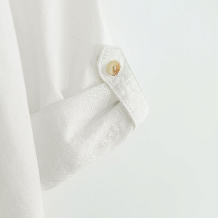 White long sleeve shirt with sleeve rolling up to a button