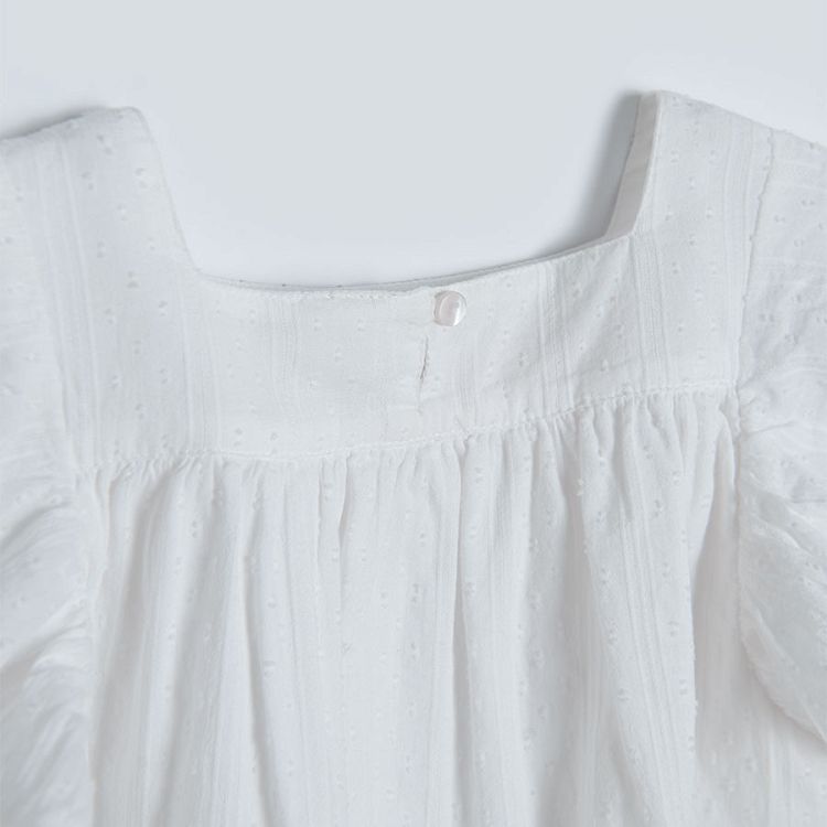 White sleeveless blouse with square embrodered neckline and ruffles on the shoulders