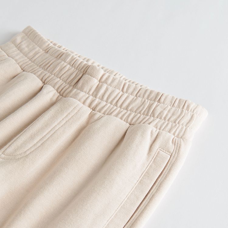 Beige jogging pants with elastic band around the waist and ankles