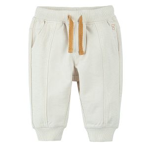 Light beige jogging pants with adjustable waist elastic band around the ankles and pockets