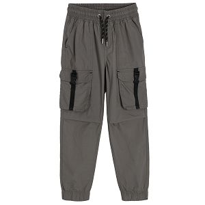 Grey trousers with external pockets and decorative clip