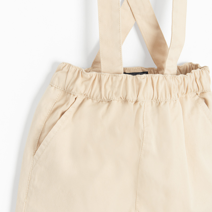 Brown bodysuit with bow tie and ecru pants with suspenders