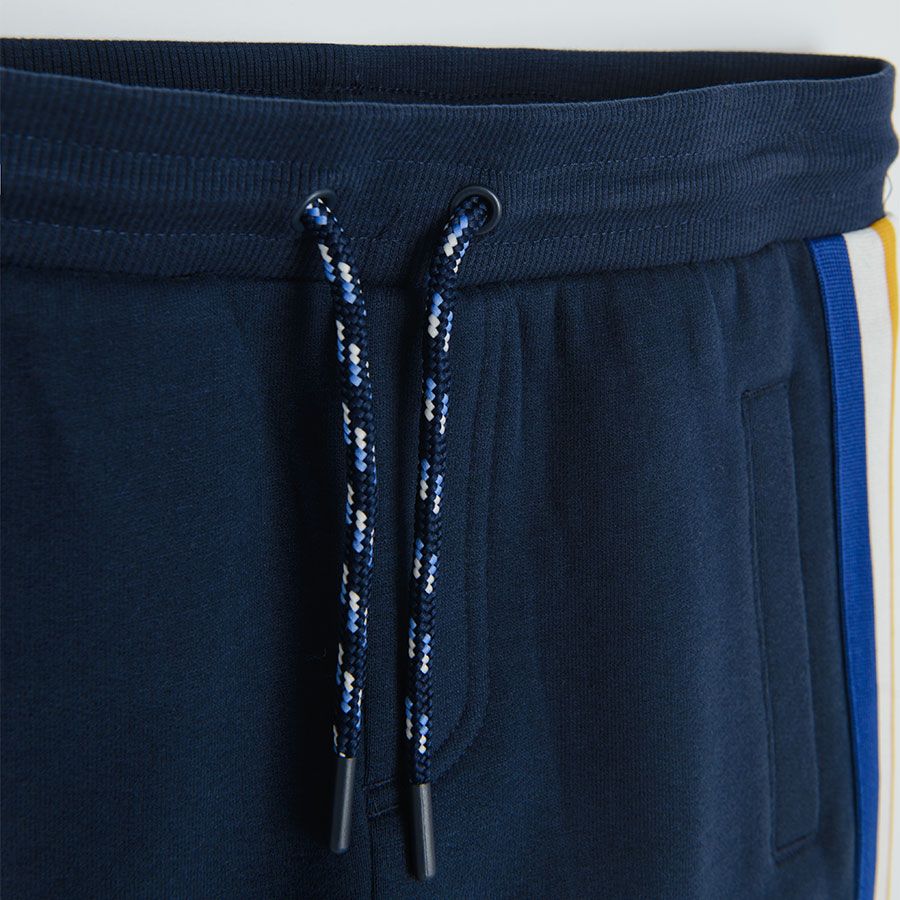 Dark blue jogging pants with yellow, white and blue stripe on the side