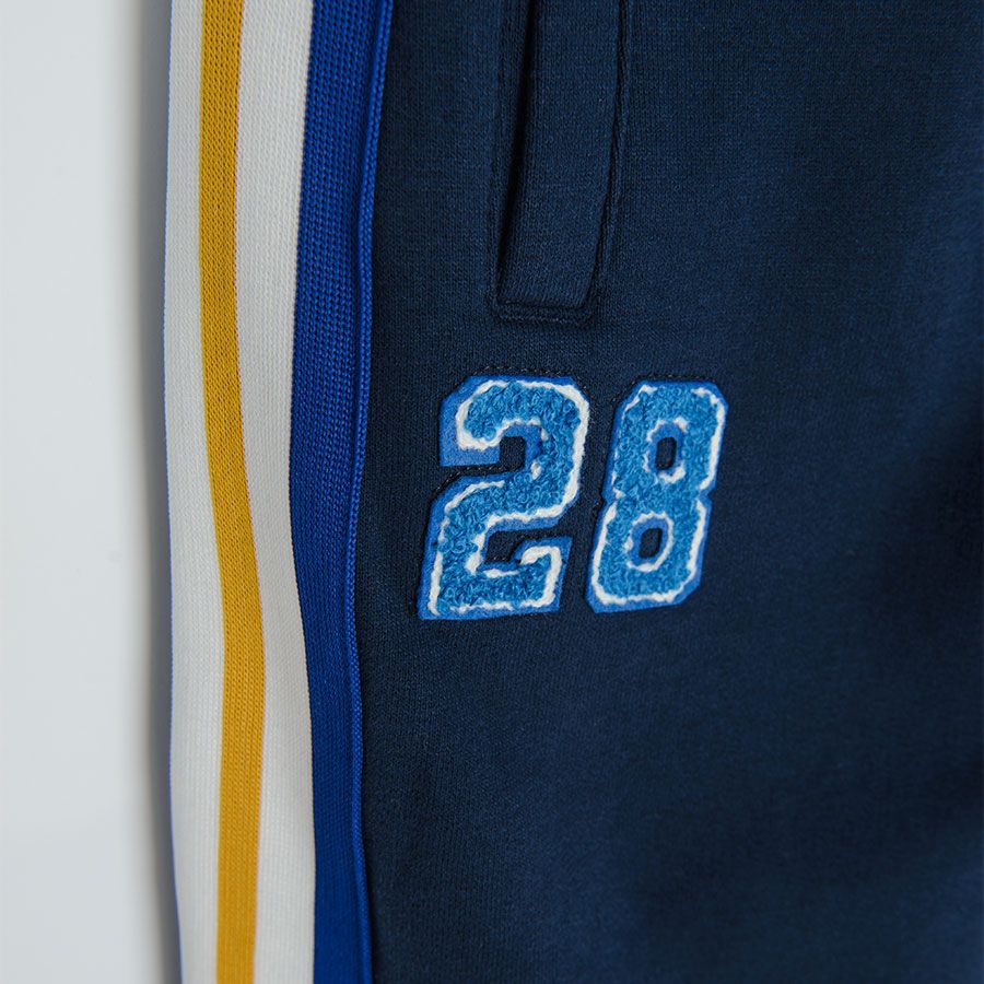 Dark blue jogging pants with yellow, white and blue stripe on the side