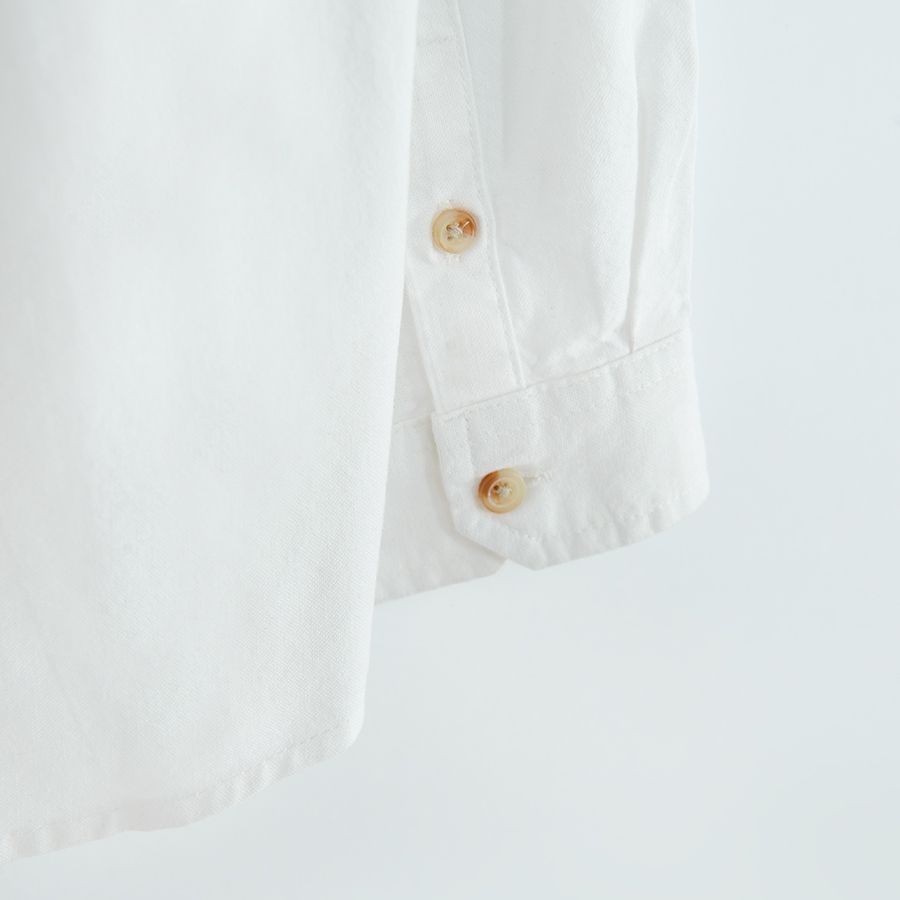 White long sleeve shirt with sleeve rolling up to a button