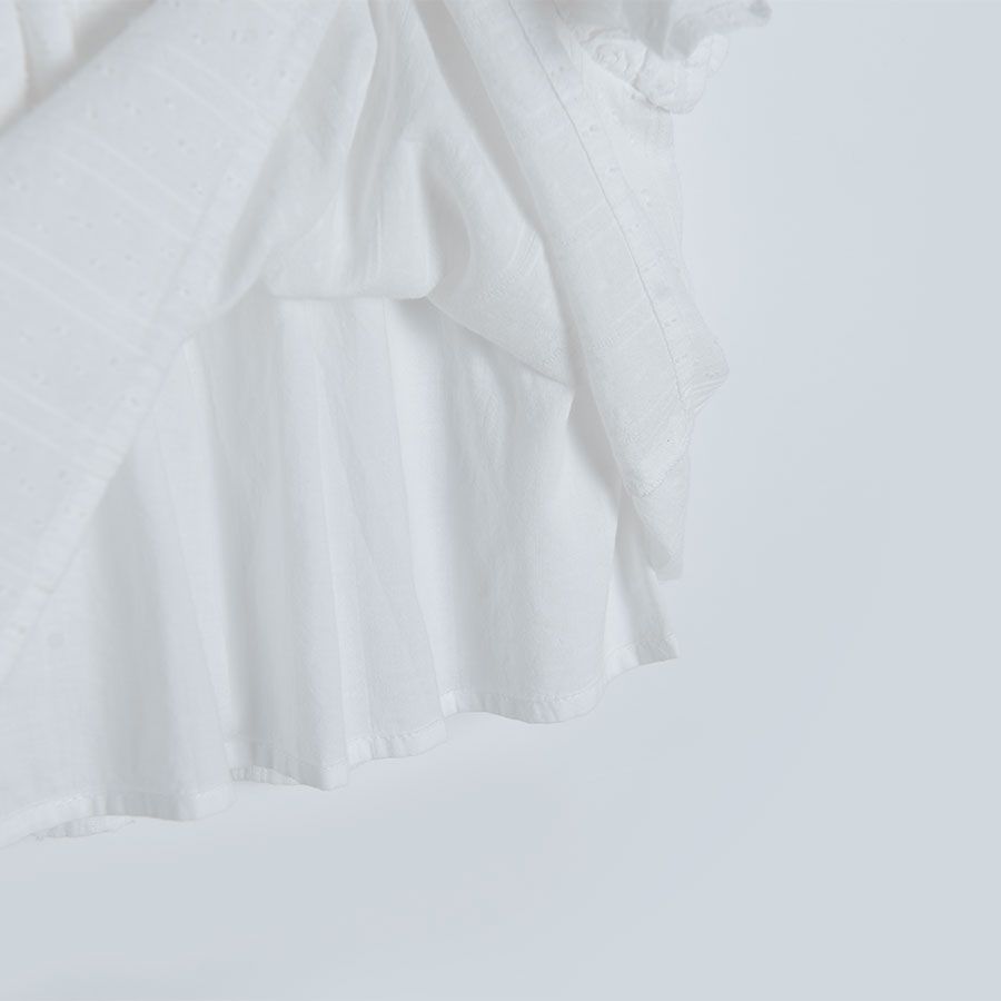 White sleeveless blouse with square embrodered neckline and ruffles on the shoulders