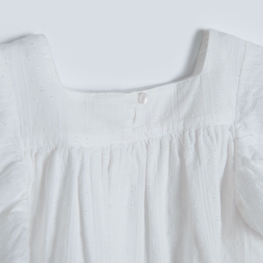 White sleeveless blouse with square embrodered neckline and ruffles on the shoulders